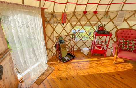Comfy seating inside Poppy Yurt with the lakeside view through the window